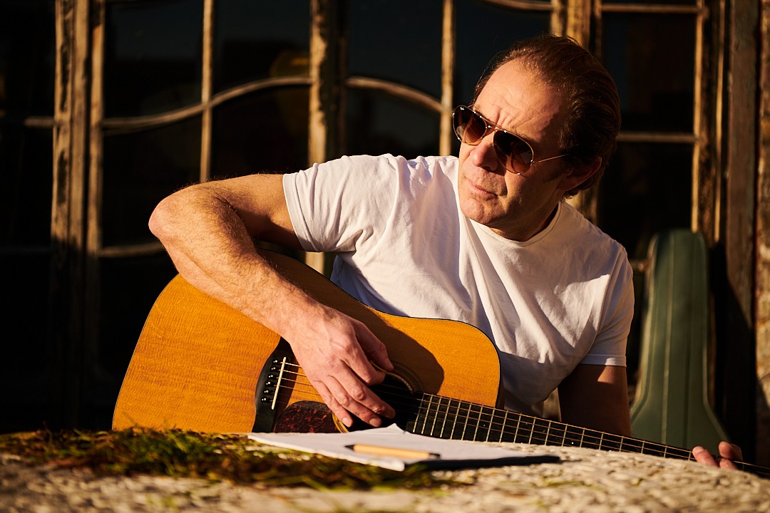 Charlie James playing guitar and writing a song in the sunlight