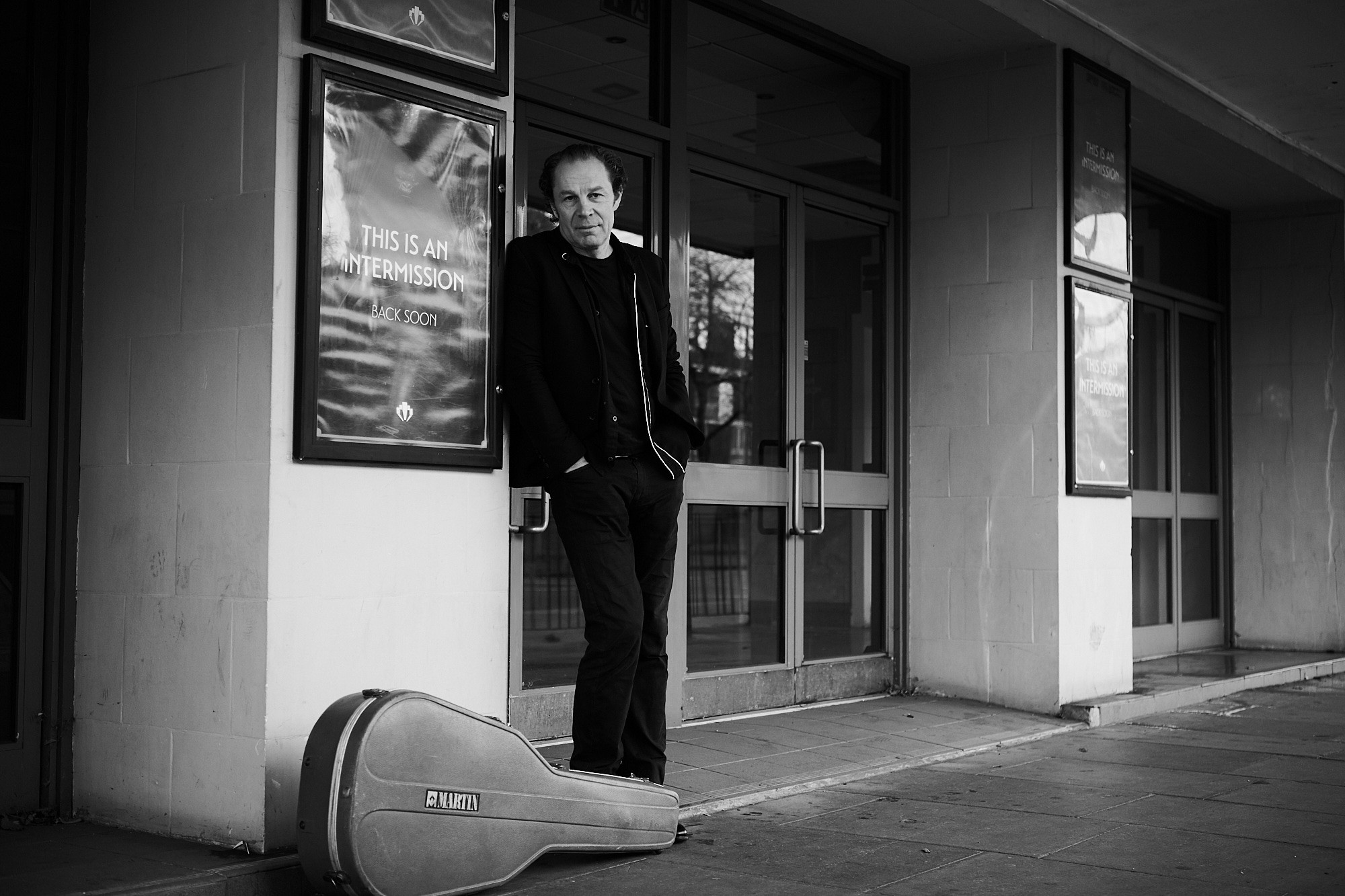 Charlie James leaning on the wall with guitar case on the floor